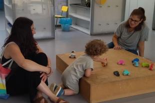 educadora i família jugant amb un infant els primers dies d'escola