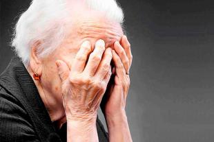 An older woman covering her face with her hands